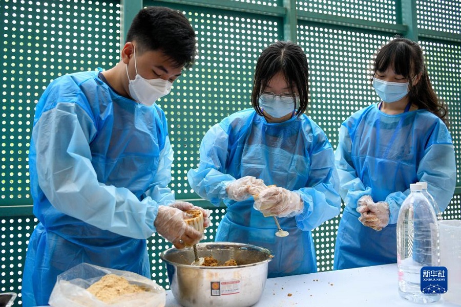 7月18日，在成都大熊貓繁育研究基地，參加體驗(yàn)營的兩岸大學(xué)生在體驗(yàn)制作大熊貓食用的窩窩頭，將和好的面粉塞入模具中。新華社記者 胥冰潔 攝